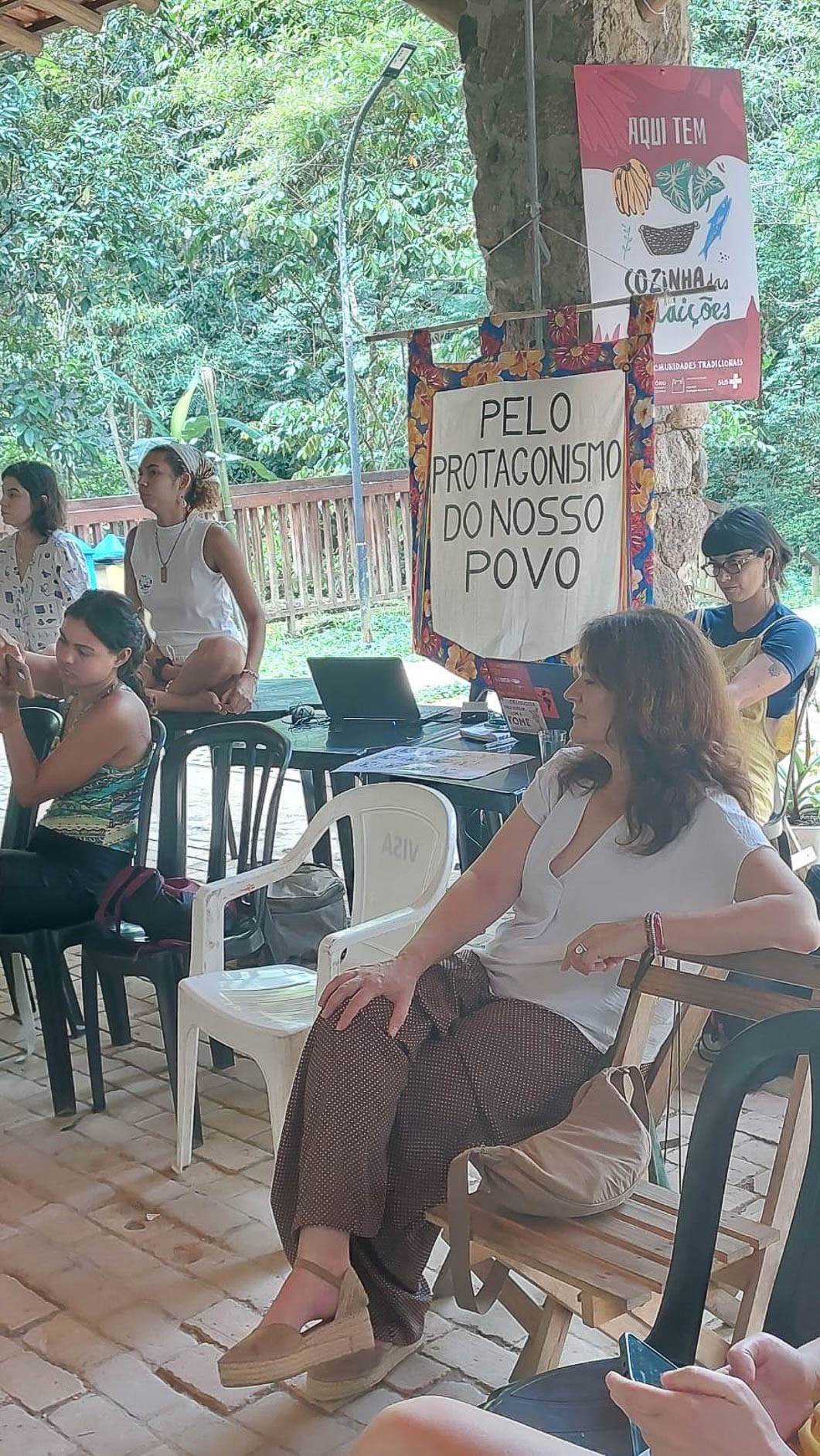 Participantes num encontro ao ar livre, junto a uma faixa com a frase «Pelo protagonismo do nosso povo».